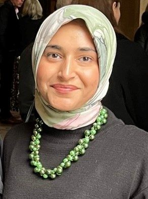 woman looking at camera wearing a green necklace and a green hijab